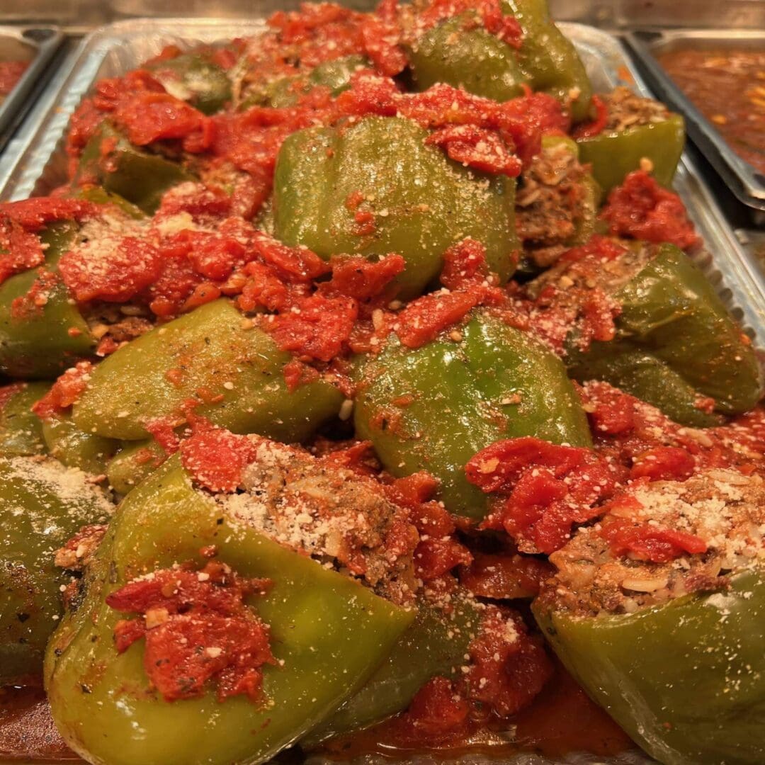 A tray of stuffed peppers with meat and tomato sauce.