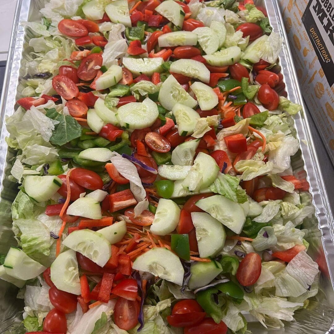 A tray of salad with tomatoes, cucumbers and lettuce.