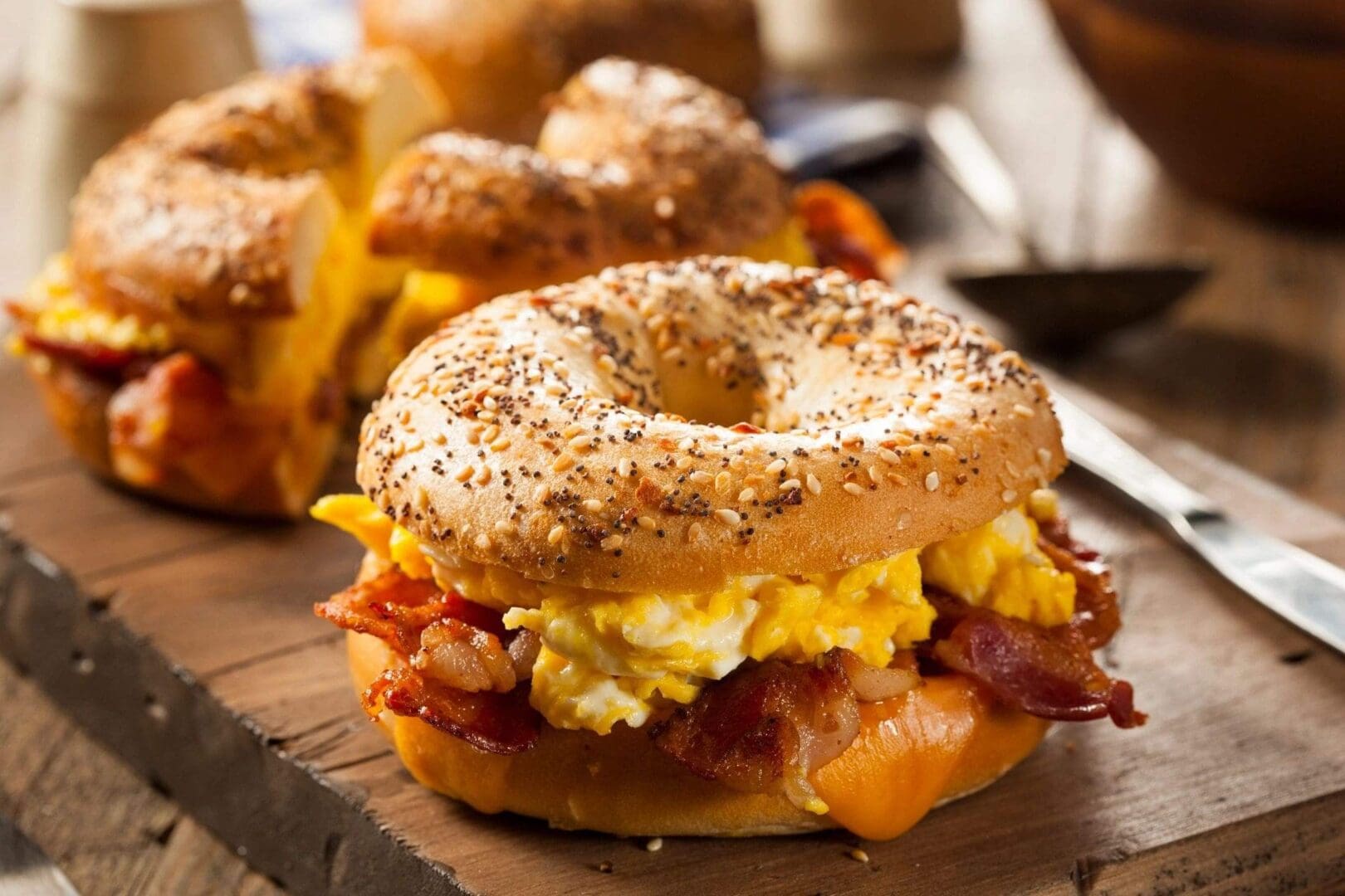 A bagel sandwich with bacon and eggs on it.