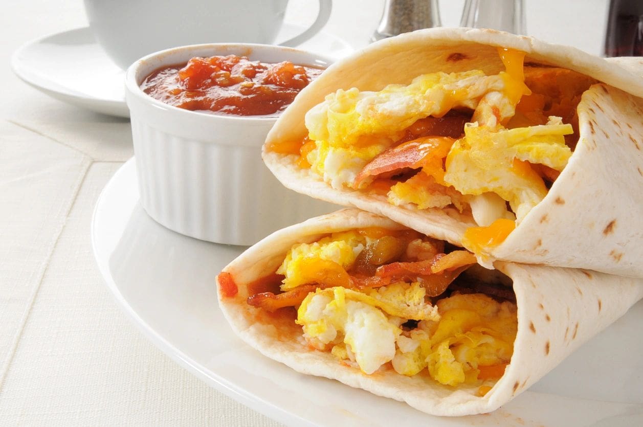 A plate with two breakfast sandwiches and salsa.